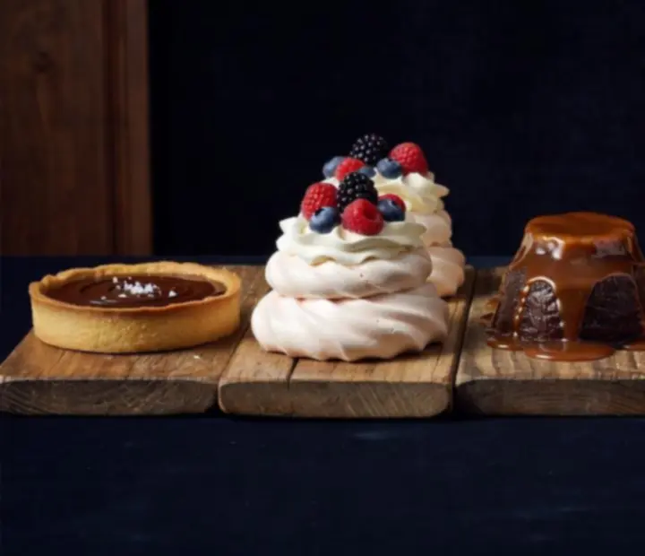 Assorted desserts lined up on a long timber table in a warm poker lounge.